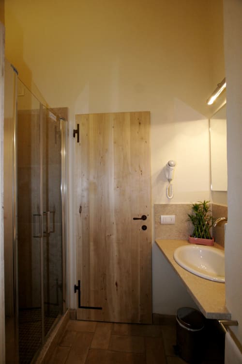 Moderno bagno a La Locanda del Vino Nobile a Montepulciano con doccia, lavandino e dettagli in legno rustico