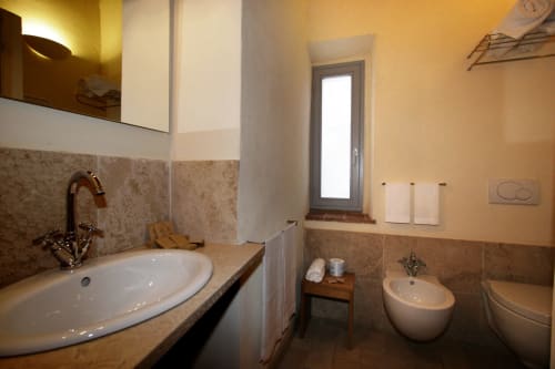 Elegante bagno della Locanda del Vino Nobile a Montepulciano con piastrelle beige, lavabo rotondo e arredi moderni