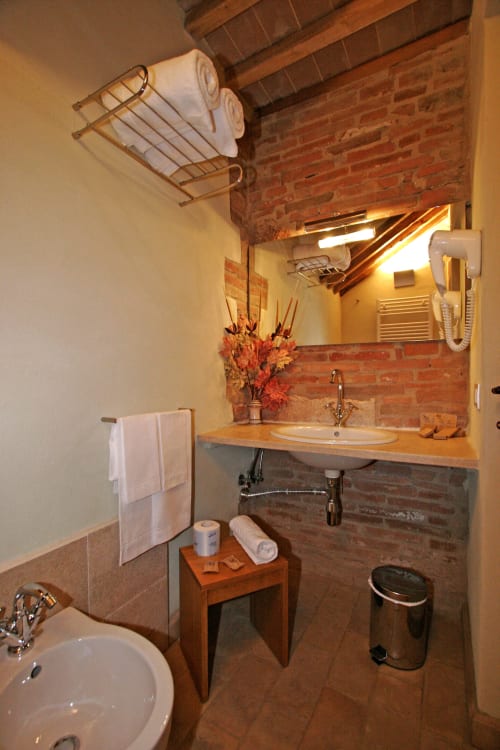 Bagno rustico con mattoni a vista presso La Locanda del Vino Nobile a Montepulciano, arredo con vanity in legno, scaldasalviette e muratura a vista