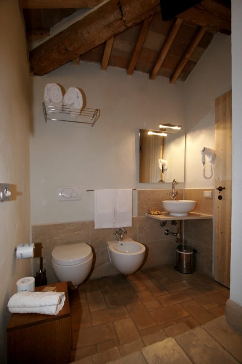 Bagno rustico a La Locanda del Vino Nobile a Montepulciano con travi a vista, doppio lavabo e pavimenti in cotto