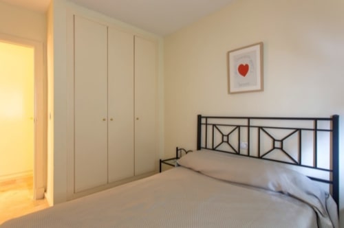 Dormitorio moderno en Wehost Costaluz de Puerto Santa María con cama de estructura metálica, armarios empotrados y cuadro decorativo de corazón