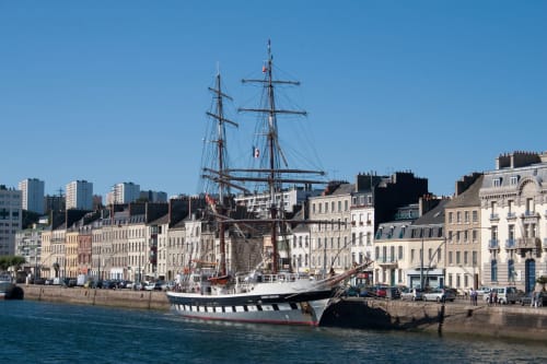 Grand voilier historique amarré au port français près du gîte La Vallée Joly au Vast, Normandie, avec bâtiments de pierre traditionnels