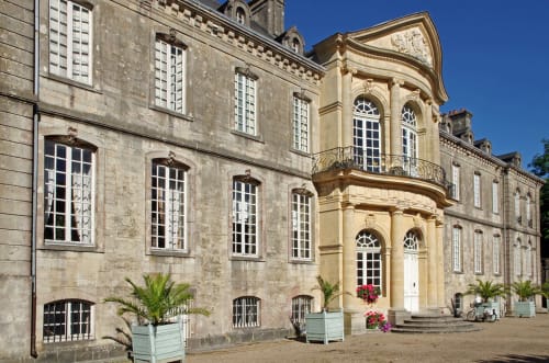 La Vallee Joly, maison d'hôtes au Vast en France, arbore des façades élégantes en pierre et crème, avec des cours soignées et des plantes en pots