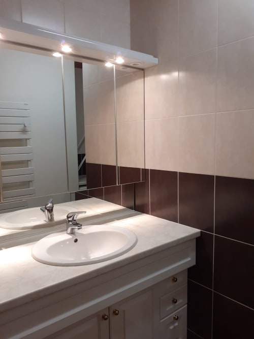 Salle de bain moderne du Chalet Les Arcosses avec double vasque, miroir de cabinet et carrelage brun