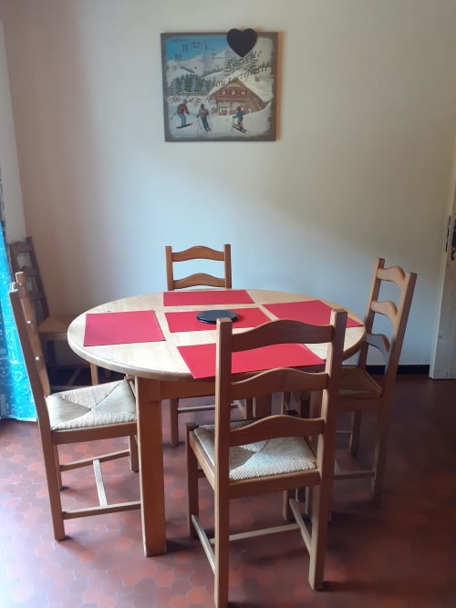 Salle à manger du Chalet Les Arcosses avec table ronde, chaises en bois et horloge vue montagne à La Giettaz