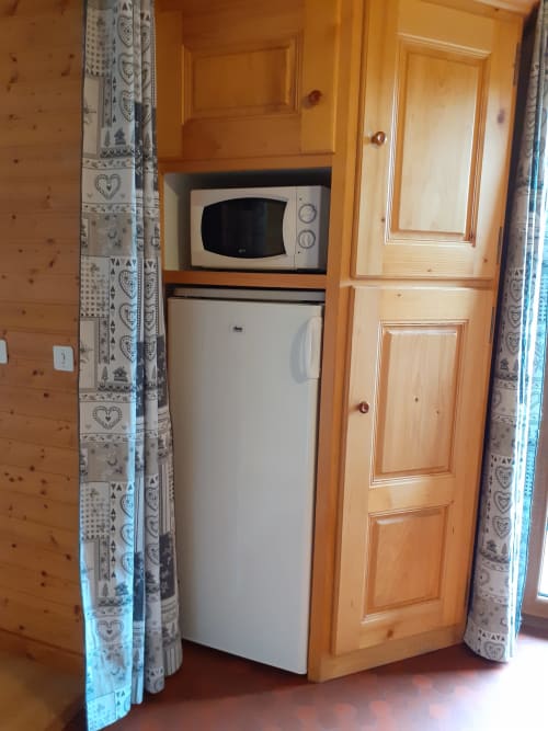 Kitchenette compacte au Chalet Les Arcosses avec micro-ondes, réfrigérateur et mobilier en bois