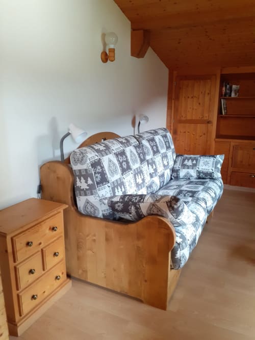 Chambre douillette au Chalet Les Arcosses avec lit en bois, literie à motifs, commode et mobilier de montagne à La