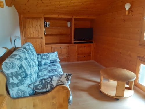 Chambre chaleureuse du Chalet Les Arcosses avec coin salon, télévision et ambiance authentique de montagne