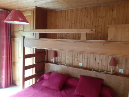 Chambre cosy en bois des Arcosses avec literie rose, lits superposés et vue montagne à La Giettaz