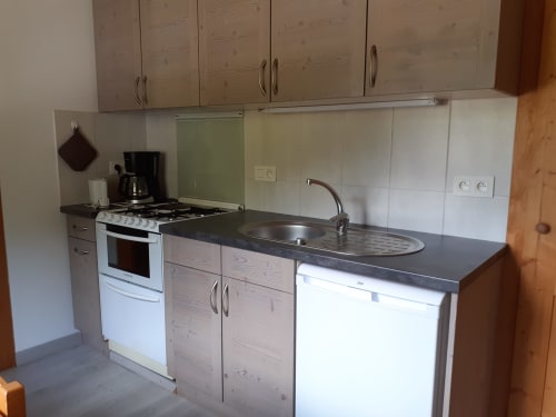 Cuisine moderne de l'appartement Chalet Les Arcosses à La Giettaz, avec cuisinière, évier, placards blancs et plan de travail foncé