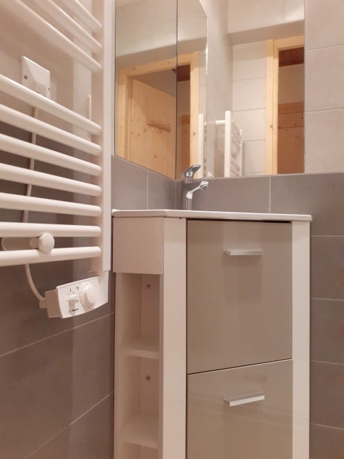 Salle de bains moderne du Chalet Les Arcosses avec sèche-serviettes chauffant, vasque, miroir et murs carrelés à La Giettaz