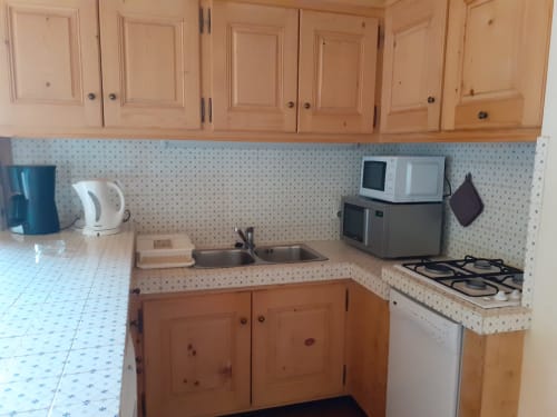 Petite cuisine de l'appartement Chalet Les Arcosses avec meubles en bois, cuisinière à gaz et petits électroménagers à La Giettaz