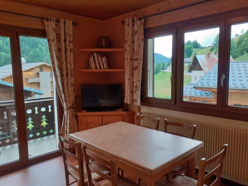 Salle à manger rustique au Chalet Les Arcosses avec vue sur les montagnes, TV et paysage alpin par les fenêtres