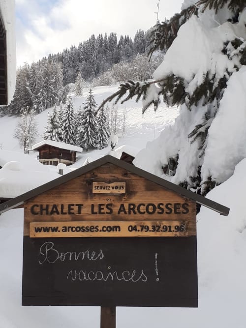 Enseigne du Chalet Les Arcosses dans un paysage alpin enneigé, La Giettaz, France