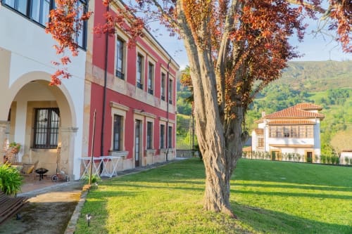 Colonial-style red and white buildings with autumn foliage at La Venta de Miyares hotel in Piloña, Spain