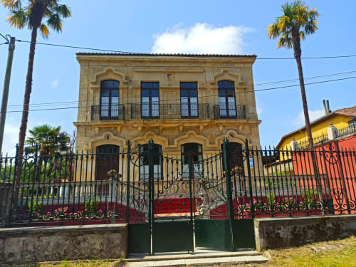 Mansión colonial La Venta de Miyares en Piloña, España, con fachada de piedra ornamentada y puertas de hierro forjado