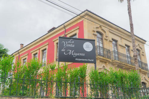 Hotel rural La Venta de Miyares con fachada colonial rosa y amarilla en Piloña, España