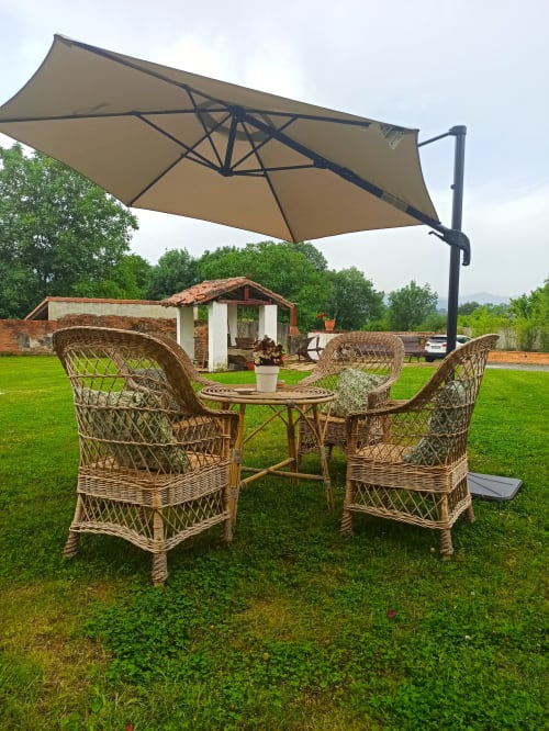 Wicker seating area with cantilever umbrella at La Venta de Miyares, Miyares hotel grounds with green lawn