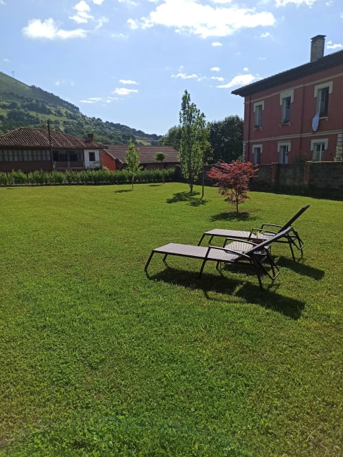 Lounge chairs on manicured lawn at La Venta de Miyares, colonial-style hotel in Asturias with mountain views
