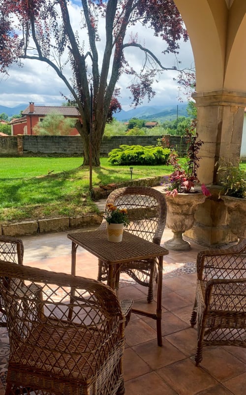 Terrace seating area at La Venta de Miyares with wicker chairs, tree, and Asturian countryside views
