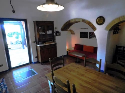 Wohn- und Essbereich des Apartments Santa Palmira mit Holztisch, Gewölbedecken und Gartenblick in Pomarance