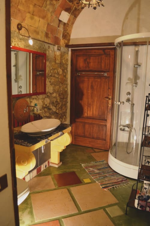 Modernes Badezimmer im Agri-Bio Santa Palmira mit runder Dusche, Holzwaschbecken und farbenfrohem Fliesenboden in Pomarance