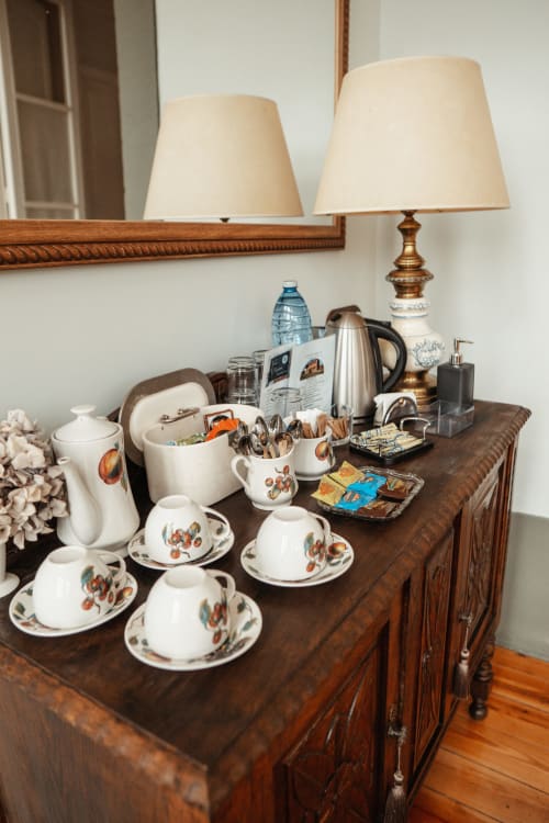 Hotel dresser with tea service, lamps, and floral dishware at La Venta de Miyares, Asturias