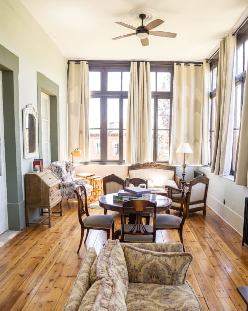 Elegant living room at La Venta de Miyares with wooden floors, period furniture, and tall windows overlooking Piloña