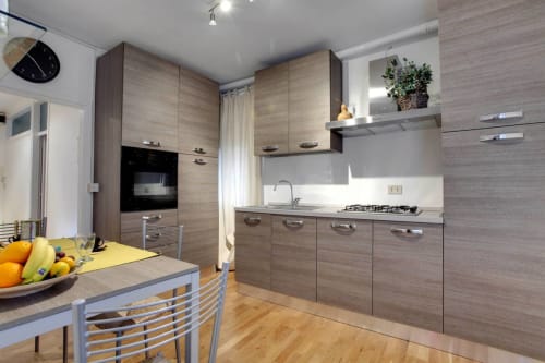 Modern kitchen with wood cabinets, stainless steel appliances, and dining area at Ca Cortigiane apartment in Venice
