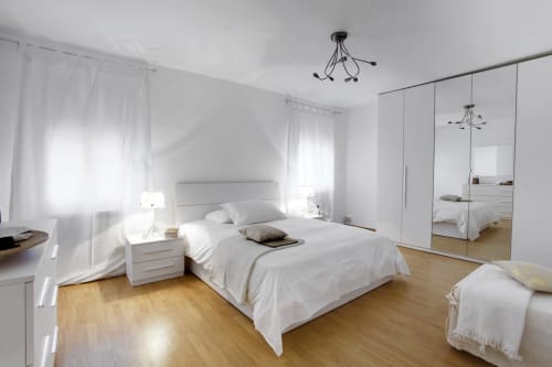 Bright modern bedroom at Ca Cortigiane, Venice with white bed, mirrored wardrobe, wooden floors and city views