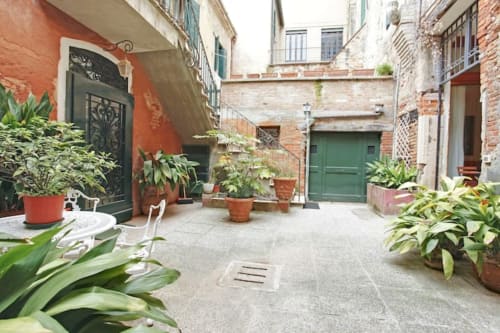 Affascinante cortile di Ca Cortigiane a Venezia con piante in vaso, porte verdi e muri in cotto
