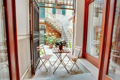 Balcone della Ca Cortigiane Suite a Venezia con tavolo, sedie e piante in vaso che si affacciano sulla corte cittadina