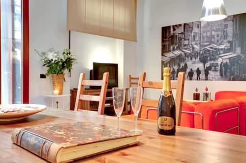 Ca Cortigiane Suite a Venezia: elegante zona pranzo con champagne, sedie in legno, camino e divano rosso con vista sulla città