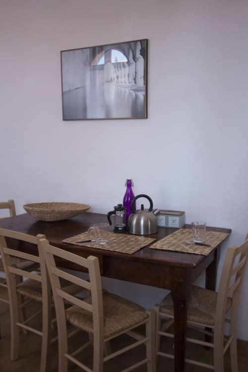 Dining area in Ca Cortigiane Venice apartment with wooden table, woven chairs, and kettle on surface