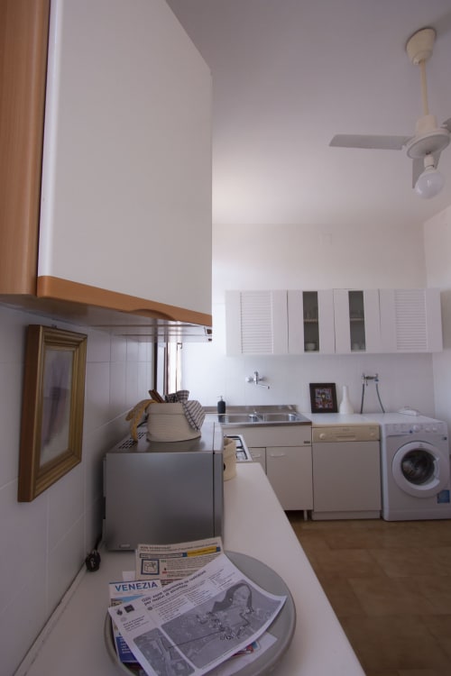 Modern kitchen at Ca Corrigiane Venice apartment with washing machine, sink, and white cabinets