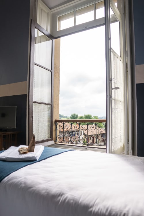 Bright bedroom with open French doors overlooking ornate balcony and countryside at La Venta de Miyares, Asturias
