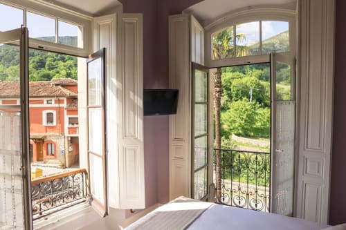 Luxury bedroom with open doors to mountain views at La Venta de Miyares hotel in Piloña, Spain