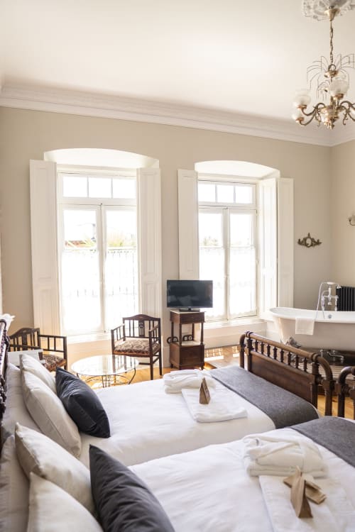 Elegant hotel room at La Venta de Miyares with twin beds, fireplace, bay windows, and bathroom in Piloña