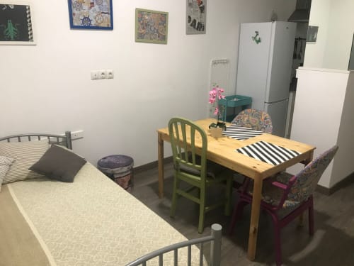 Dormitorio verde de apartamento con dos camas, mesa de madera, sillas verdes y cocina en Apartamentos Huelintown, Málaga