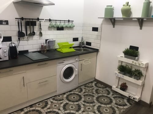 Cocina moderna en Apartamento Green de Huelintown Málaga con muebles blancos, encimera negra, lavadora y bien organizada