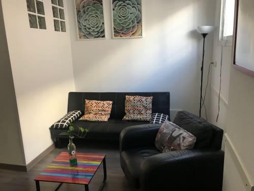 Sala moderna de Apartamentos Huelintown en Málaga con sofá sectional negro, cojines coloridos y mesa de café arcoíris