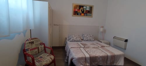 Acogedor dormitorio en Apartamentos Huelintown de Málaga con cama doble, silla roja y comodidades modernas