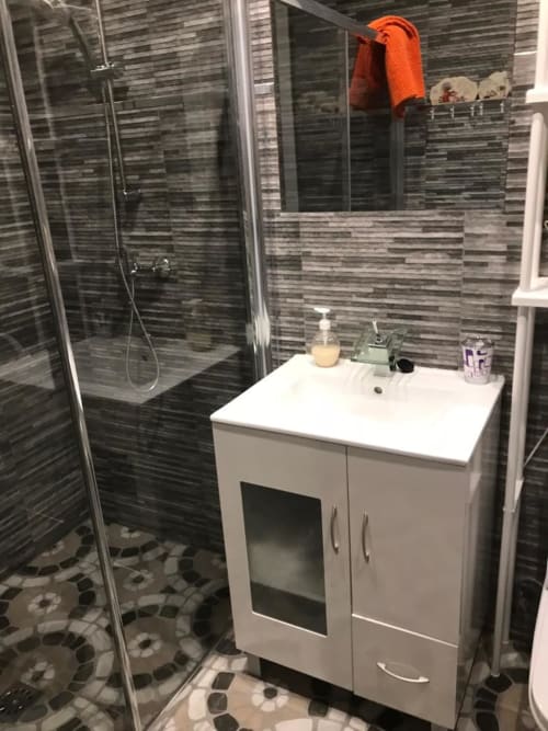 Baño moderno en Apartamentos Huelintown, Málaga con ducha a ras de suelo, lavabo blanco y azulejos grises