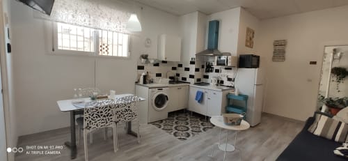 Moderna zona de cocina-salón en Apartamentos Huelintown, Málaga, con comedor, lavadora y mobiliario contemporáneo
