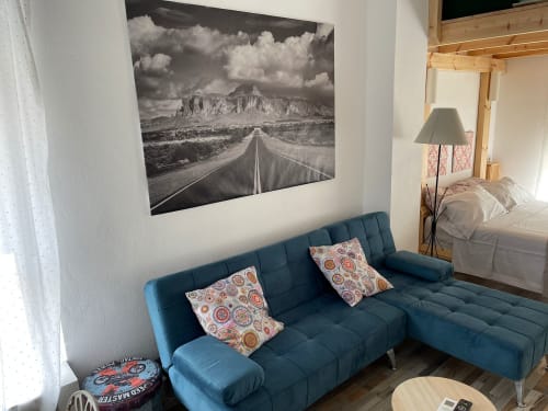 Sala de estar moderna con sofá azul, cojines decorativos y cuadro de paisaje montañoso en blanco y negro