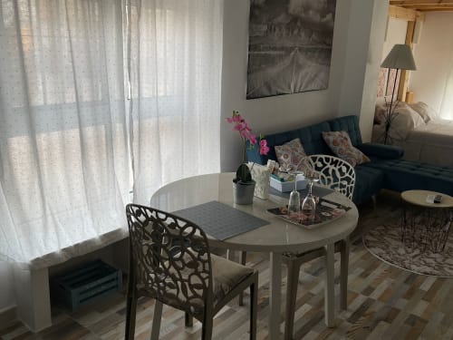 Sala de estar moderna en Apartamentos Huelintown en Málaga con mesa de comedor, sofá turquesa y vistas al jardín