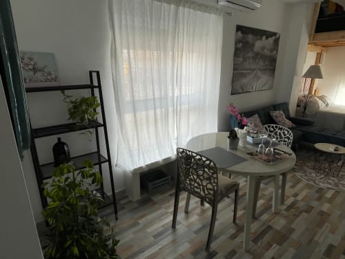 Moderna sala de estar en Apartamentos Huelintown, Málaga, con mesa de comedor, plantas en macetas y vista al jardín