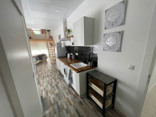 Moderna cocina en Apartamentos Huelintown, Málaga con muebles blancos, encimera de madera y salpicadero negro