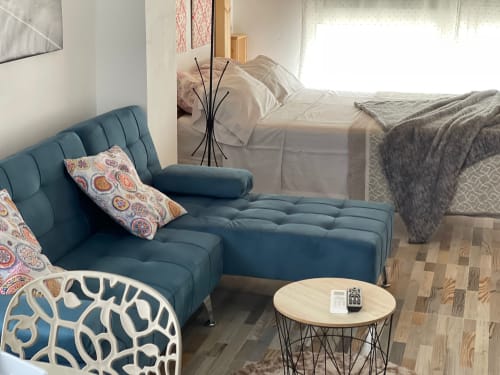 Moderno estudio en Apartamentos Huelintown, Málaga con sofá turquesa, mesita de madera y cama con vista al jardín