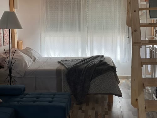 Dormitorio luminoso en Apartamentos Huelintown, Málaga, con cama queen, mobiliario moderno y vistas al jardín